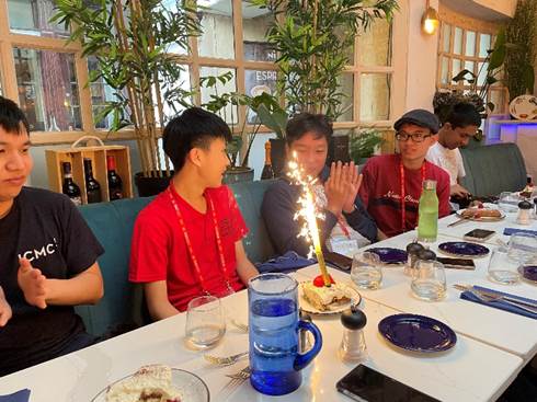 A group of people sitting at a table with a cake and candles